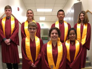 seven high school students dressed in maroon robes with gold