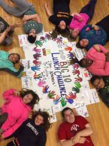 students lying on the floor surrounding a colorful poster