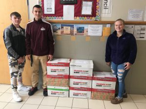 students standing in front of christmas boxes they made for the troops