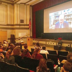 video chat with an engineer is projected on a screen in a high school auditorium