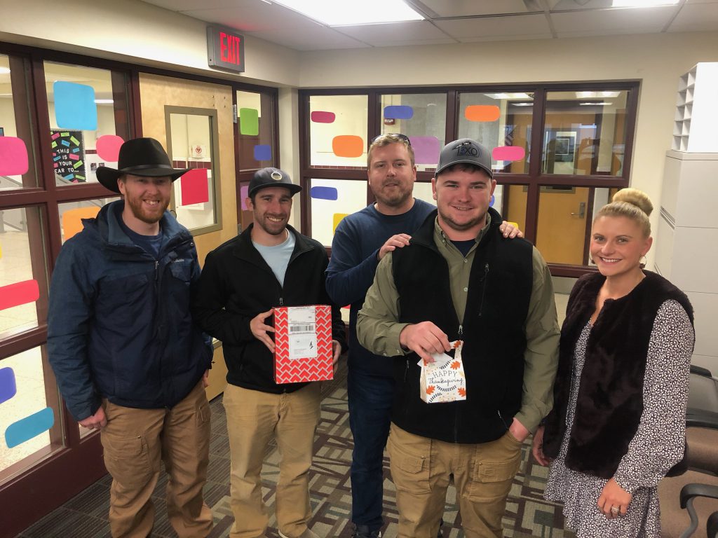 four company representatives and a school counselor hold up gift cards