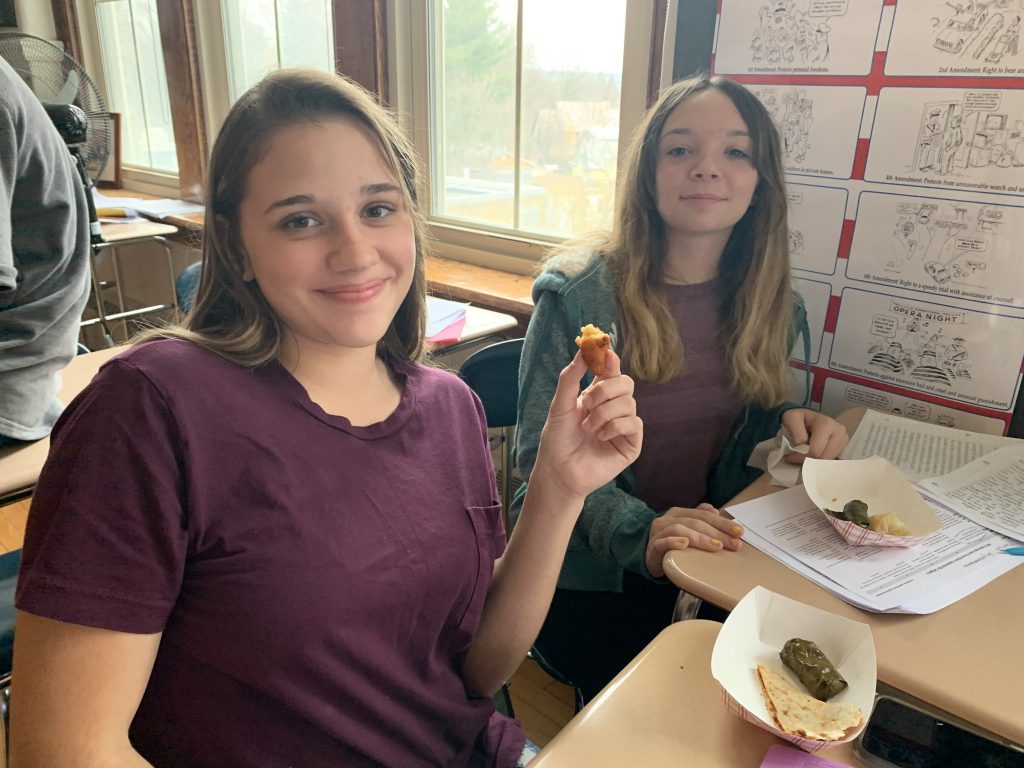 students sample foods at their desks in a school classroom