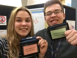 two high school students show their badges as poll inspectors 