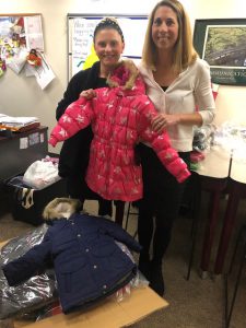 school counselor and principal hold up child's winter coat