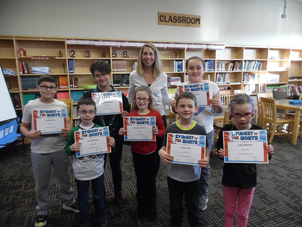 Seven students and an elementary school principal stand in two rows in a school library