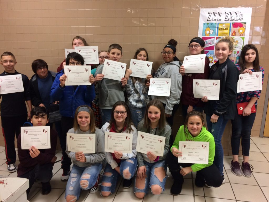 Group of high school students hold certificates in a school hallway