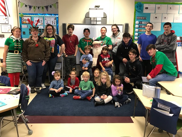 group picture of senior class members with kindergarten students and Santa Claus in an elementary classroom