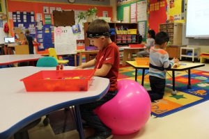 kindergarten student sits on an exercise ball