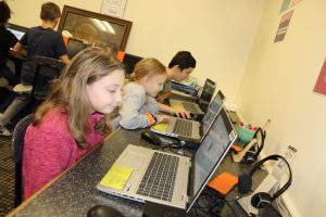 students seated at laptops in an elementary school computer lab