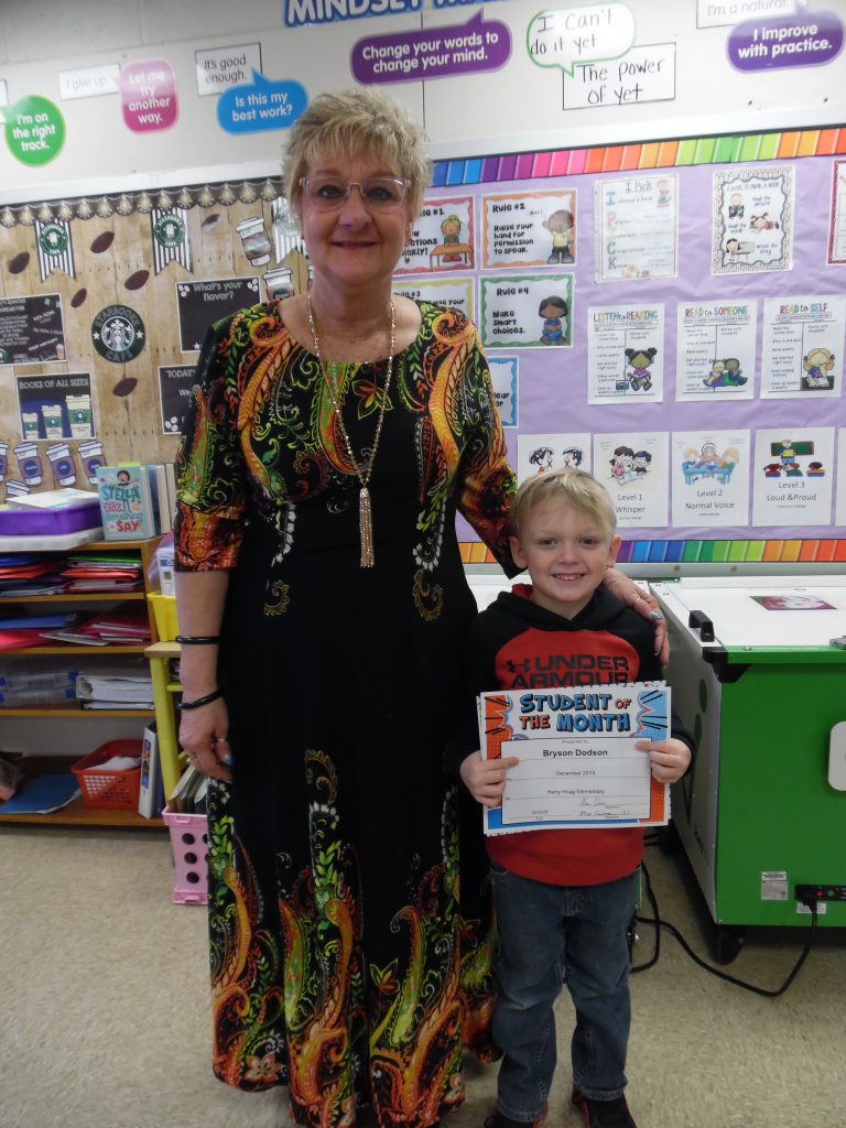 student holds a certificate while standing next to a literacy specialist