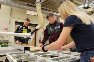 Three students use a table saw 