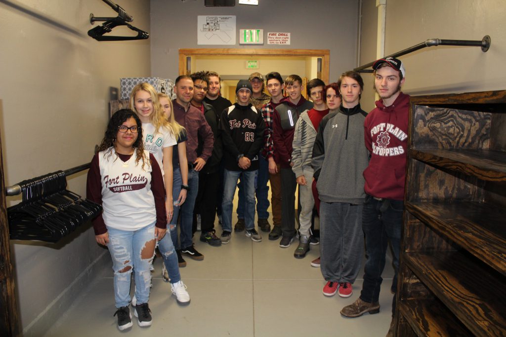 Group of students and their teacher stand inside a large walk-in closet space