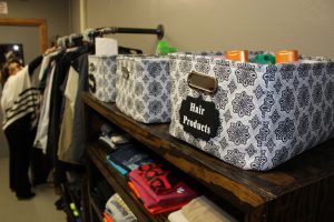 a person organizes clothes on a clothing rack in a walk-in closet filled with shelves and bins