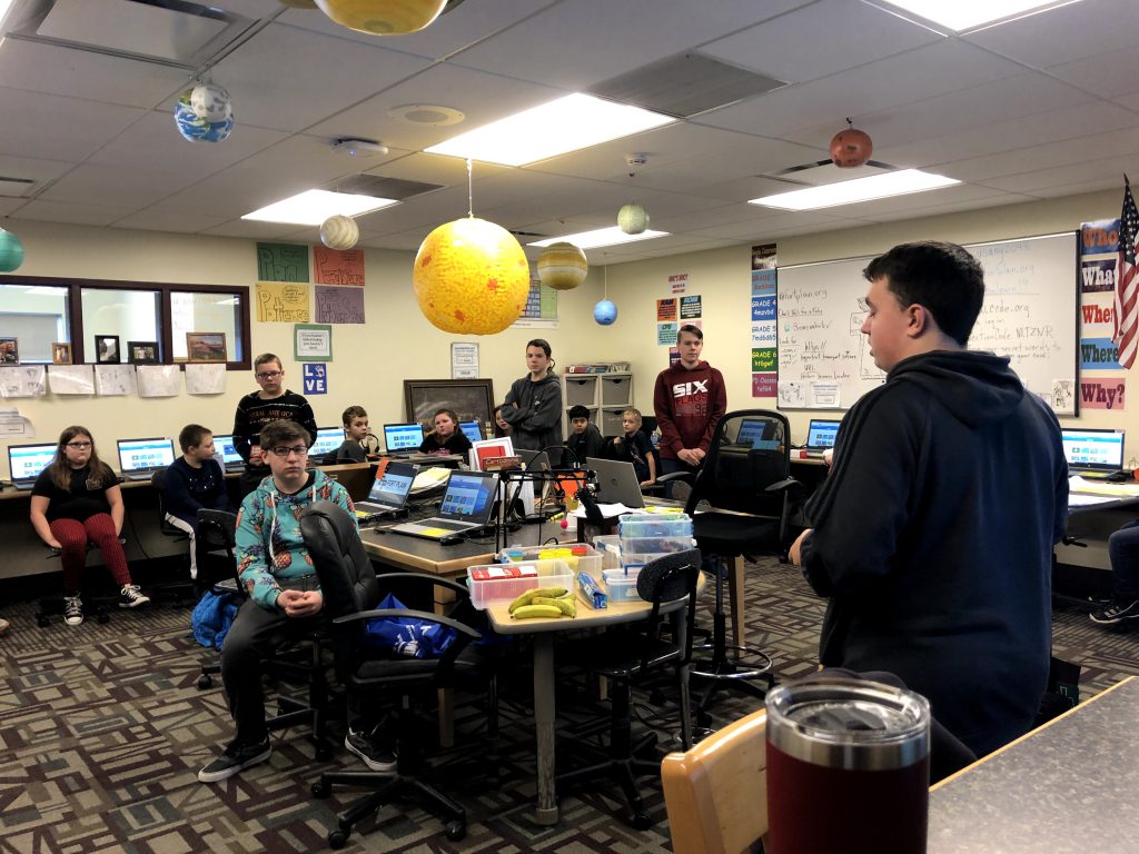 high school student leads a lesson for fourth graders in a school computer lab