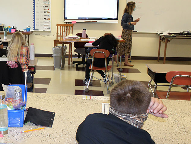 teacher instructing in front of seated students in classroom