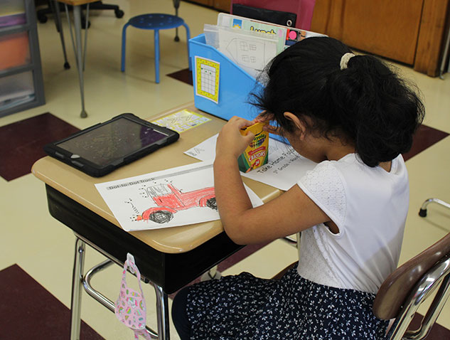 student coloring with crayons at desk