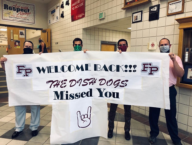 staff holding banner Welcome Back The Dish Dogs Missed You