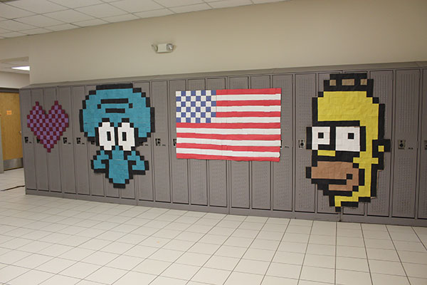 student-created artwork of a heart, a face, a flag, Homer Simpson displayed on lockers