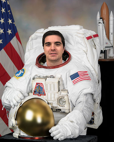 Patrick wearing a space suit, holding helmet