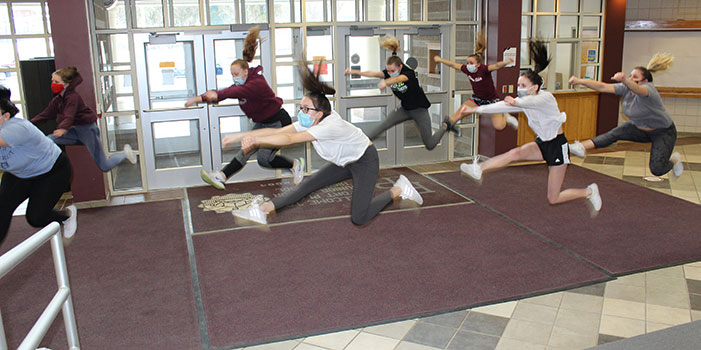 cheerleaders leaping during practice in HS lobby