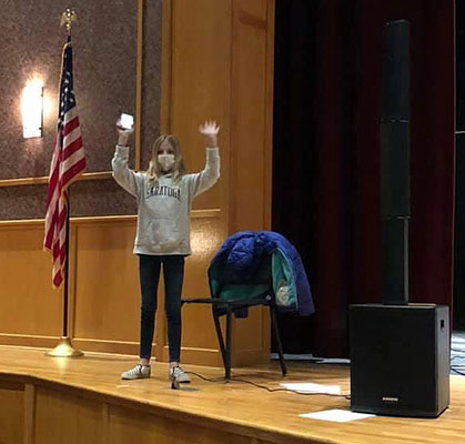 student on stage with her hands in the air