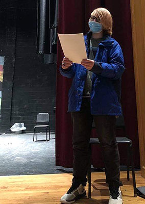 student reading script, standing on stage