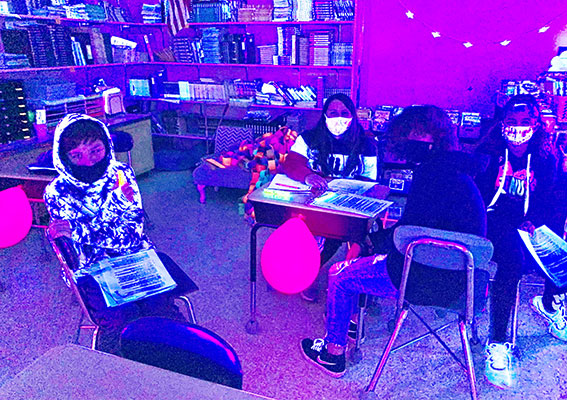 teacher and students in blacklighted classroom