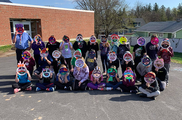 group of students and teacher holding their Kachina Masks in front of their faces