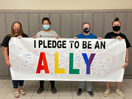 advisor and students holding Ally banner