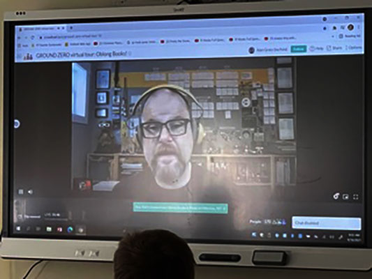 Alan Gratz on video screen talking to students in classroom