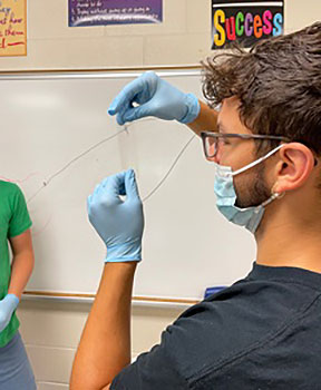 A student holds a fiber and looks at it