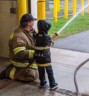 Firefighter and student holding a hose