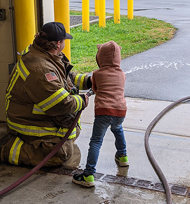 Firefighter and student holding a hose