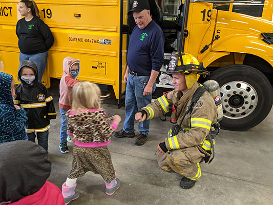 Firefighter kneeling to greet a Pre-K student