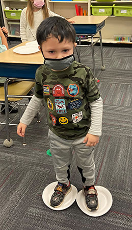 Pre-K student skating on paper plates