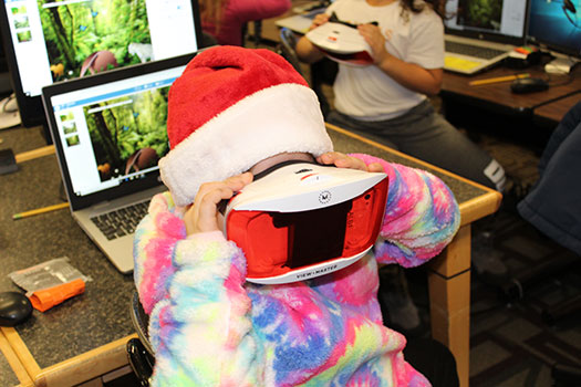 student wearing hat looking into VR goggles