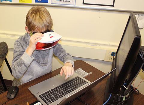 student typing on pc keyboard while looking into VR goggles