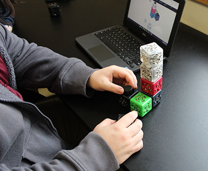 student's hands and cubelet robots