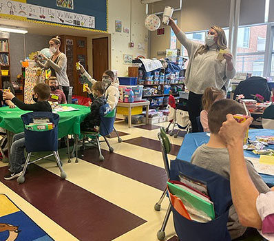 students and teacher toasting with fruit juice boxes