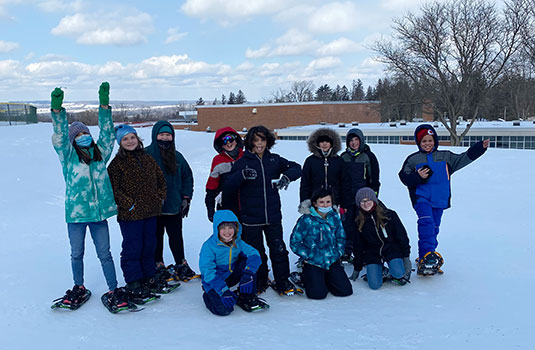 group of students wearing snowshoes standing in the snow
