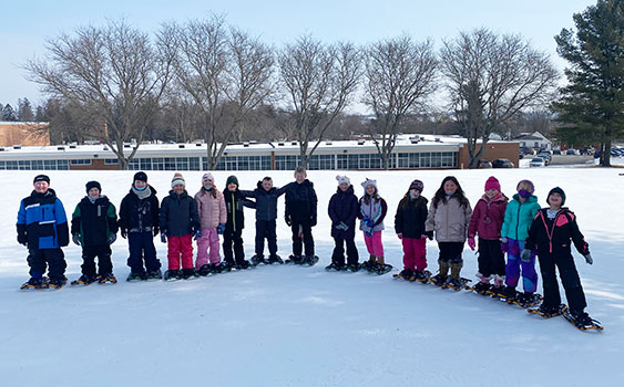 students wearing snowshoes standing in a group