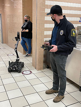 officer operating a robot that's holding a water bottle