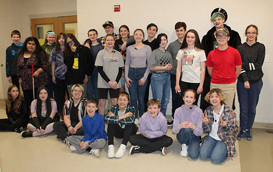 drama club students standing and sitting in a group