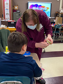 Danielle shows model of teeth to a student