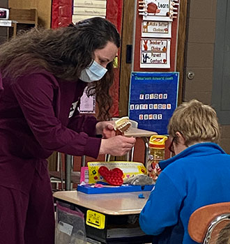 Katelyn shows model of teeth to a student