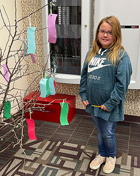 student standing next to wish tree