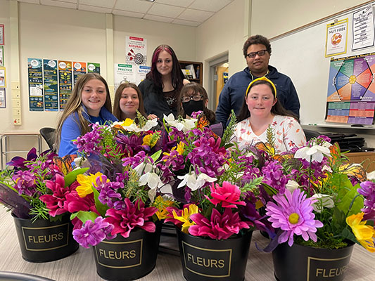 students standing behind floral centerpieces