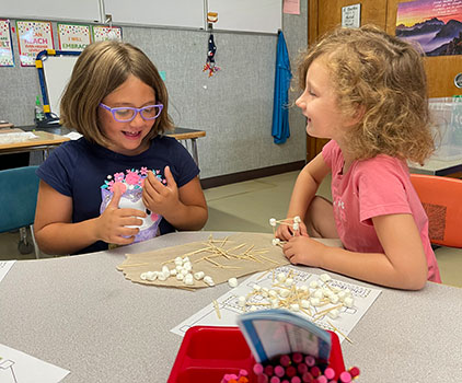 two students working with marshmallows and toothpicks