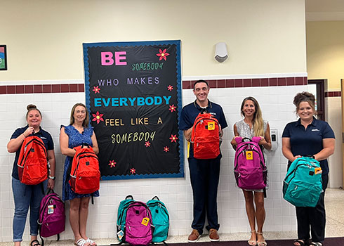 5 adults standing with backpacks
