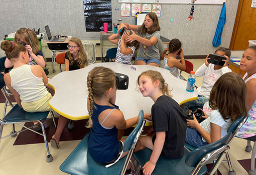 students around a table, wearing virtual reality goggles